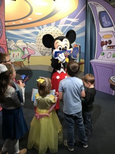 Mickey autographs while charmed kiddos look on with wonder